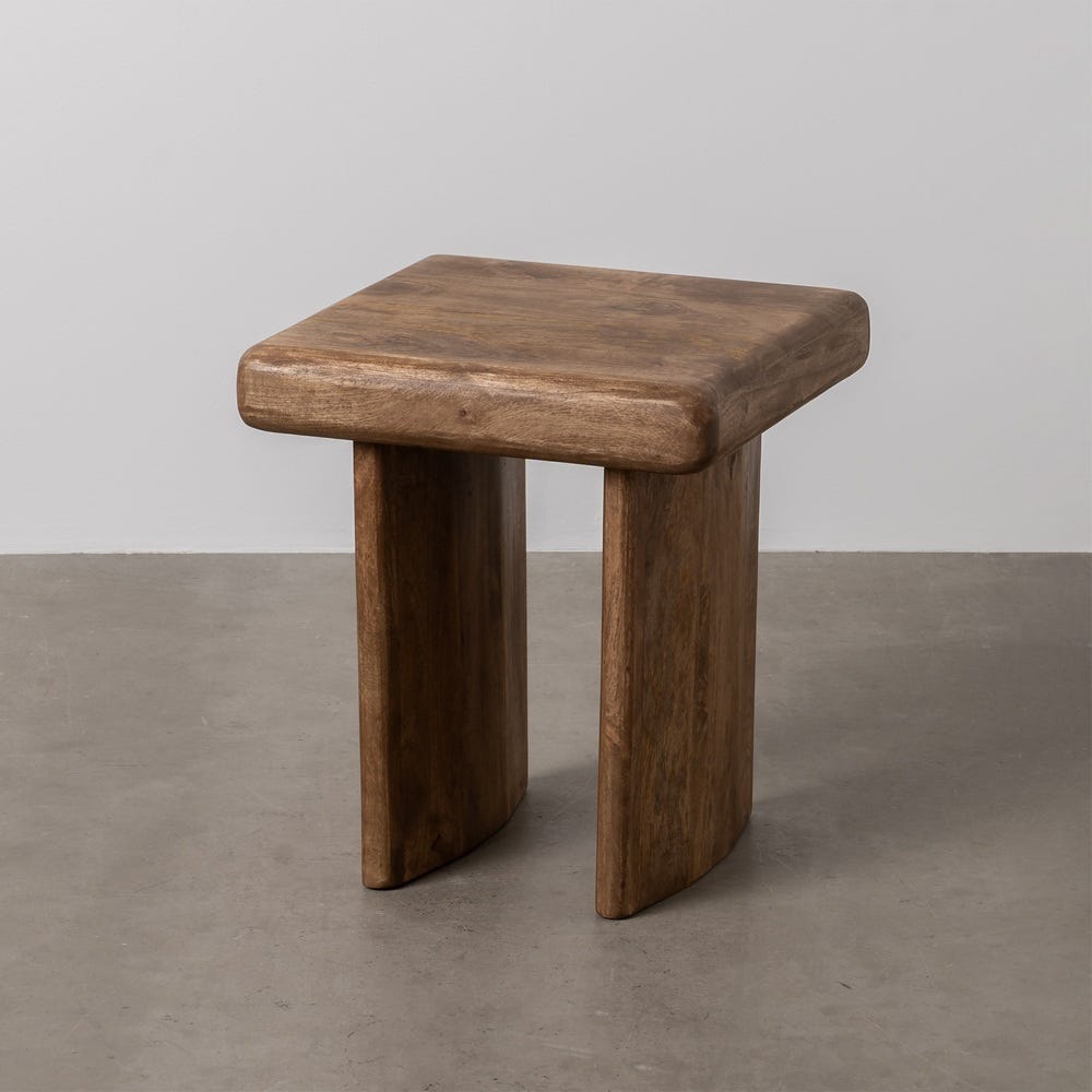 La Mesa auxiliar de madera de mango marrón Malva cuenta con un asiento rectangular y dos patas anchas y curvas, añadiendo elegancia rústica al suelo gris.