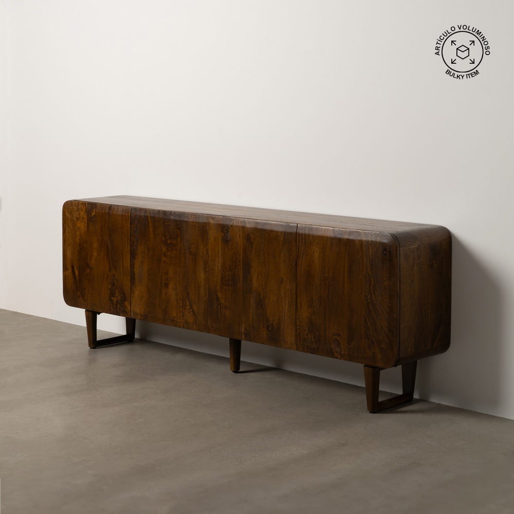 El Aparador Madera Mango Marrón Casi se alza contra una pared blanca sobre un suelo de hormigón. Es una pieza rectangular larga con tres compartimentos y cuatro patas cortas, que muestra un diseño moderno rústico y ofrece un almacenamiento eficiente.
