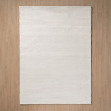  La alfombra moderna Brisa, una alfombra blanca rectangular lisa, realza un suelo de madera clara con estilo moderno, añadiendo sencillez y elegancia a cualquier decoración de interiores.