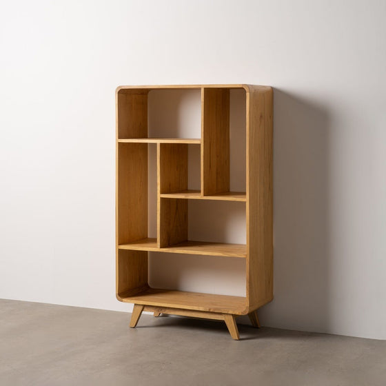La estantería moderna en madera mindi Modigo cuenta con un diseño geométrico con múltiples compartimentos abiertos, elaborados en madera de mindi. Se alza elegantemente sobre un piso gris contra una pared blanca, encarnando un estilo minimalista.