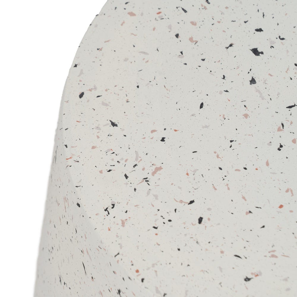 Primer plano de una superficie texturizada en la Mesa auxiliar en fibra de magnesio Blanca Martina, Ø47 x 51 cm, que presenta pequeñas motas negras, grises y rosas para un diseño intrincado.