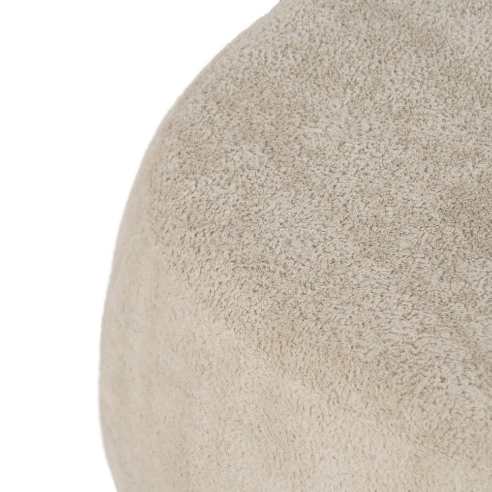 Primer plano de la esquina de un objeto de tela texturizada color beige, probablemente un Puf en Borreguito Beige Lumo, entregando comodidad y estilo como el complemento ideal para cualquier espacio.