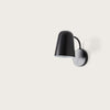 Lámpara de pared minimalista de color negro, con diseño redondeado y fácil instalación sobre fondo liso blanco. Aplique de pared Dobi