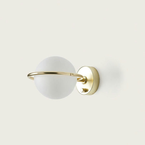 El aplique de pared Abbacus es una moderna lámpara de pared dorada con un globo redondo de vidrio esmerilado y un elegante anillo dorado, ideal para quienes aprecian la iluminación minimalista.