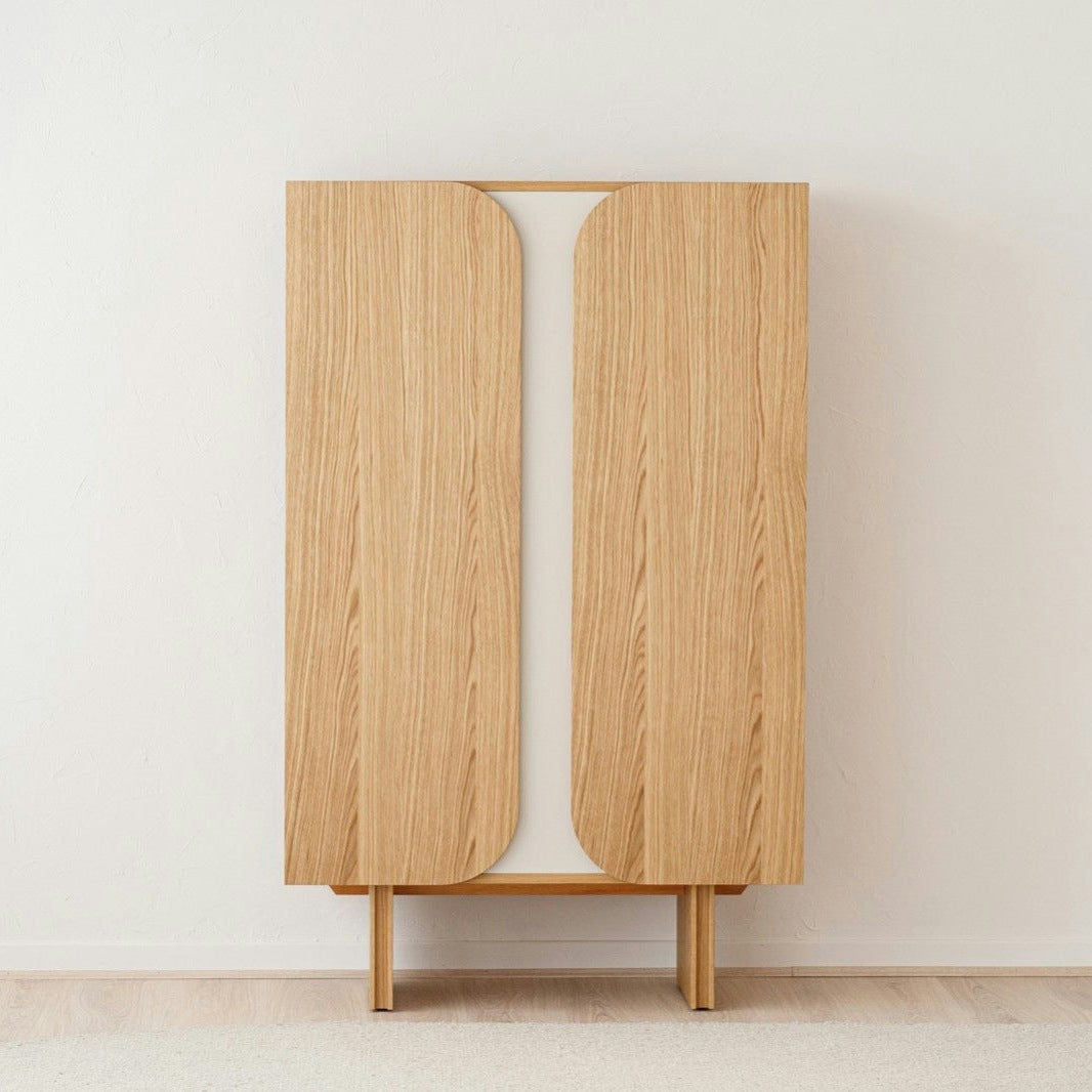 El Armario Moderno Roble Natural con Estantes - Curva, con puertas de esquinas redondeadas, se encuentra sobre un piso alfombrado claro contra una pared blanca lisa, agregando un toque perfecto de diseño contemporáneo.