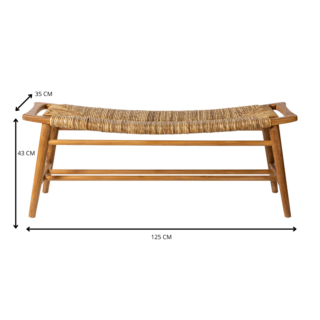 La Banqueta de Madera de Teca y Ratán Anyam (120 cm) presenta un asiento de ratán tejido y estructura de madera de teca, con unas medidas de 125x35x43 cm, y está inspirada en el diseño de BANQUETA ANYAM 120.