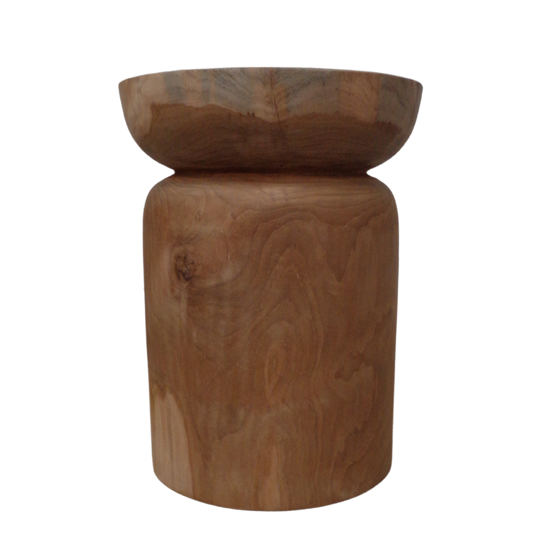 El Puff redondo en madera de teca natural Bubutan, con su tapa redonda y base cilíndrica que muestra una veta de madera natural, sirve como una elegante pieza decorativa.
