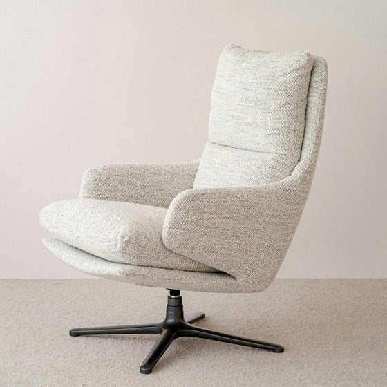La Butaca Giratoria en Mezclilla Beige Claude, con un tapizado gris moderno con un respaldo alto y asientos acolchados sobre una elegante base de metal negro, complementa perfectamente la alfombra Mezclilla Beige Claude.