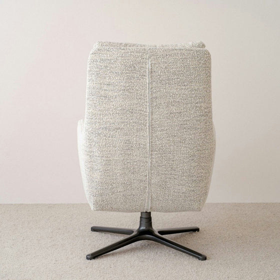 Vista posterior de una silla giratoria tapizada en gris con base de metal negro sobre la alfombra Butaca Giratoria en Mezclilla Beige Claude.