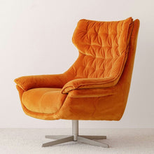  La Butaca Giratoria Tapizada en Terciopelo Naranja presenta un respaldo alto y una base giratoria plateada, mostrando un diseño moderno sobre un fondo blanco liso.