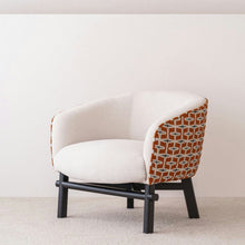  Butaca en Madera y Tapizada Beige Naranja Actis, un sillón blanco con patas negras y tela estampada en naranja y blanco en los costados, muestra elegancia y funcionalidad. Perfectamente contra una pared blanca lisa, su diseño versátil combina estilo y comodidad a la perfección.