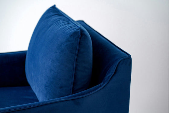 Deléitese con la elegancia de la Butaca en Terciopelo Azul Noche Helia, que presenta un lujoso cojín que encarna lujo y comodidad sobre un fondo blanco inmaculado.