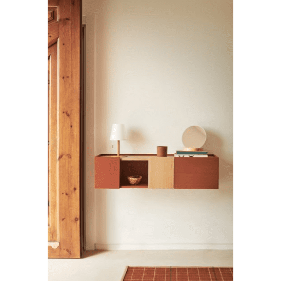 Un recibidor minimalista con Consola Otto 2P2C suspendida, diseñada como mueble moderno, con estante abierto y lámpara, junto a una pared lisa en blanco y una puerta de madera.