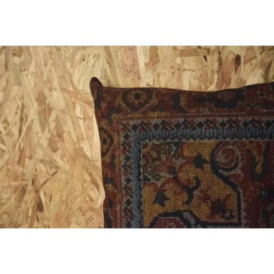 Un Cojín Algodón Lana en Ocre y Bordado Azul con una alfombra encima de un piso de madera adornado con un diseño de Bordado Azul, agregando un toque de elegancia a la Decoración en Algodón y Lana de la habitación.