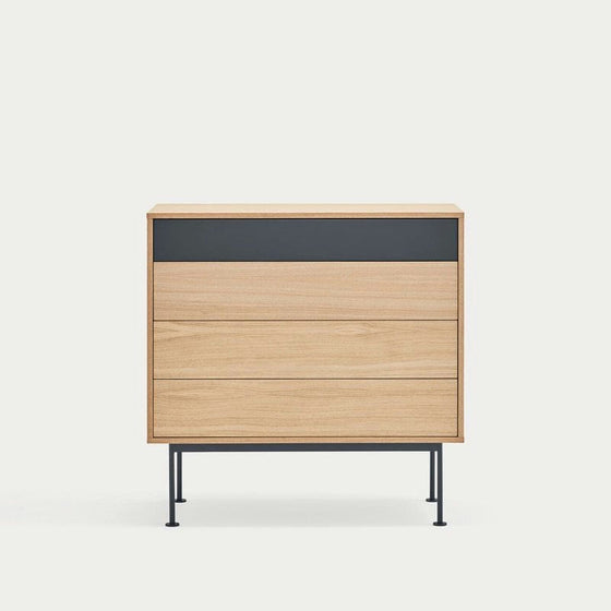 La Cómoda en MDF y Roble con 4 Cajones Yoko 4C, con sus delgadas patas de metal negro y cuatro cajones, personifica el diseño minimalista sobre un fondo sencillo, proporcionando soluciones de almacenamiento contemporáneas.