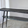 La consola Lena Metal Negro Mármol Verde tiene una estructura de metal negro, una parte superior rectangular y un estante inferior ovalado. Combina bien con alfombras claras y detalles de mármol verde para darle un toque elegante y contemporáneo a tu espacio.