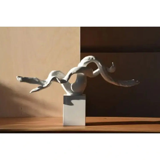 La Escultura Abstracta Rama Cerámica Blanco - Elegancia Zen está sentada sobre una mesa frente a una ventana, exudando una esencia zen.