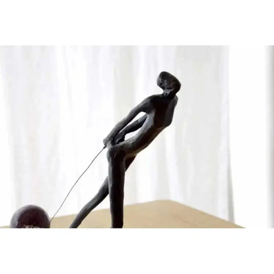 Una Escultura Arrastre de una mujer sosteniendo una uva sobre una mesa de mármol.