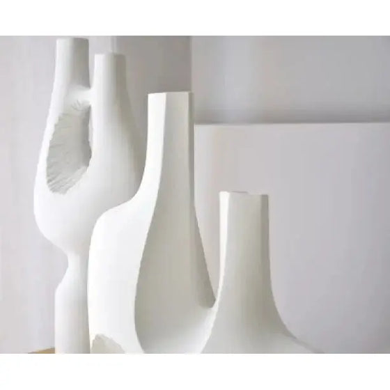 Tres jarrones blancos sobre una mesa de madera, que muestran su artesanía cerámica única y su diseño minimalista. Perfectos para añadir un toque de elegancia a cualquier espacio, estos jarrones pertenecen a la "Escultura Cerámica Artesanal Colección Vacío. Pieza 2. Textura Blanca".