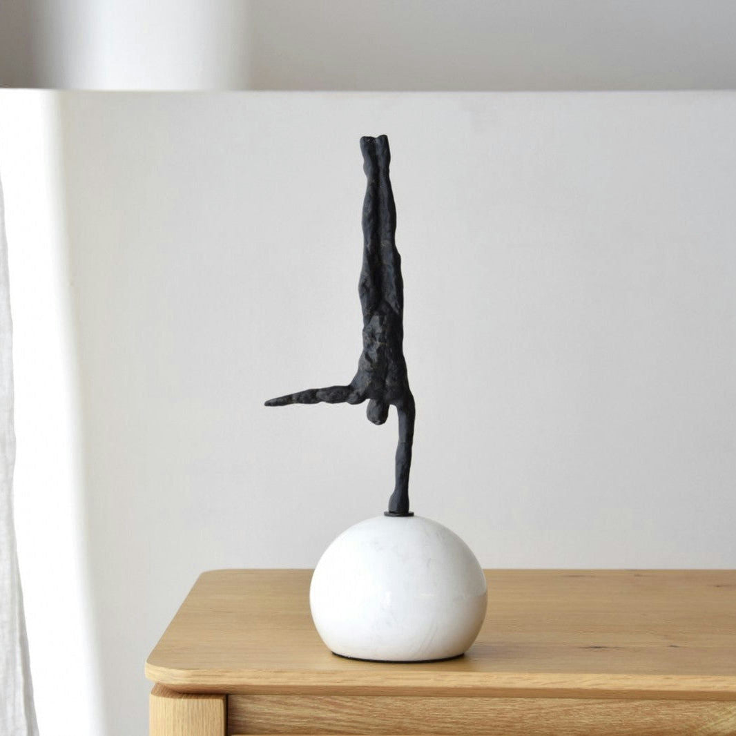 La Escultura Equilibrio N2: Metal y Mármol encarna el arte abstracto con su pequeña escultura negra que se apoya en una esfera blanca, elegantemente colocada sobre madera. Su diseño contemporáneo añade elegancia moderna a cualquier espacio.