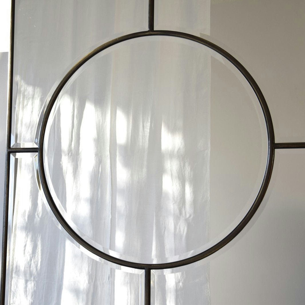 El Espejo Decorativo de Suelo - Círculo, con su marco circular de metal que muestra un diseño geométrico, se asienta elegantemente contra una cortina blanca transparente, permitiendo que la luz suave se filtre.