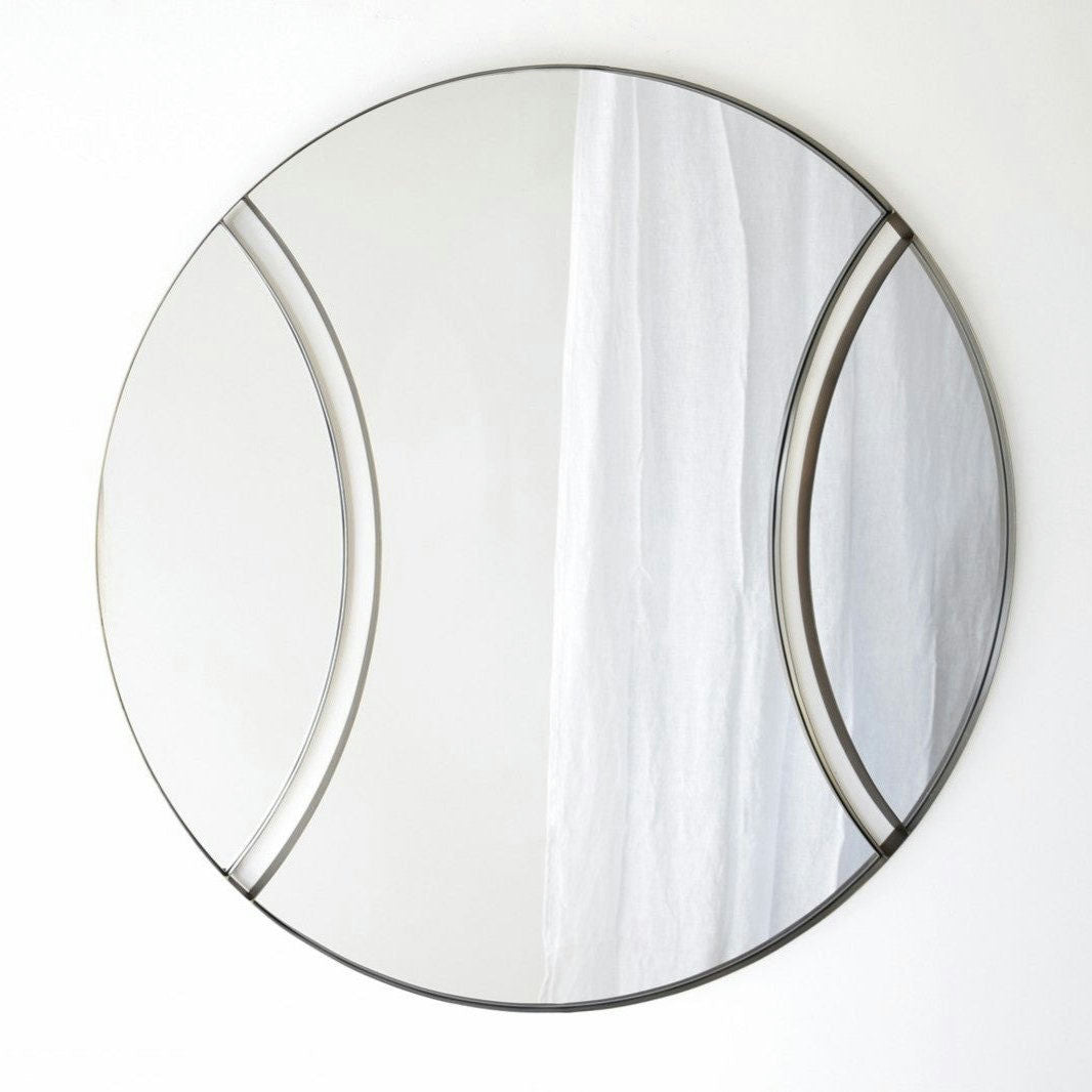 El Espejo Redondo 1 presenta un marco de metal semicircular de latón envejecido, que refleja una cortina blanca.