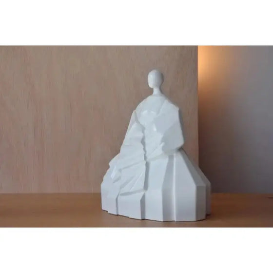 Una Figura Cerámica Japonesa Manga Extendida Blanco Brillo sobre una mesa de madera.