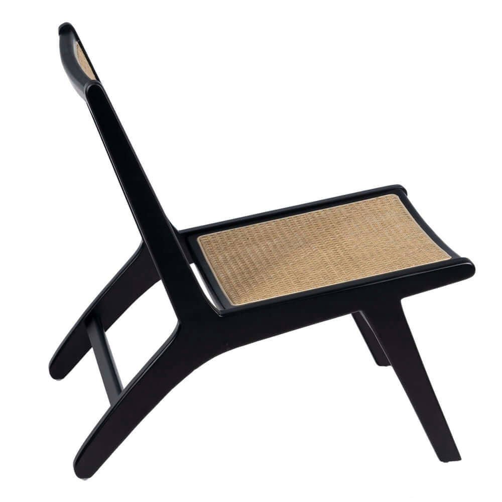 El Sillón en Madera y Ratán "Noir" es una moderna silla de madera negra con un asiento de ratán tejido, con una vista lateral en ángulo que encarna el estilo modernista al mismo tiempo que ofrece confort tradicional.