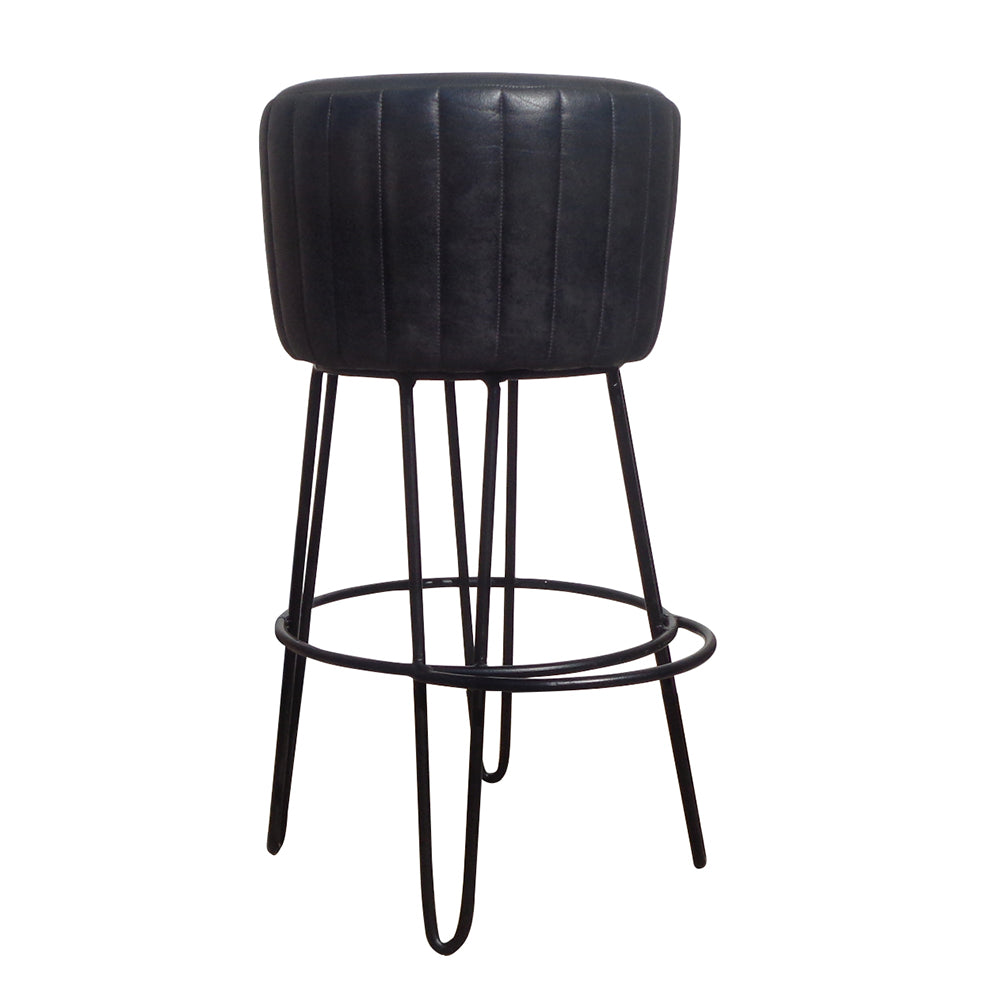 El Taburete alto metal y piel 77cm Club muestra un estilo industrial elegante con su asiento de cuero negro, estructura de hierro robusta, patas de metal y reposapiés circular.