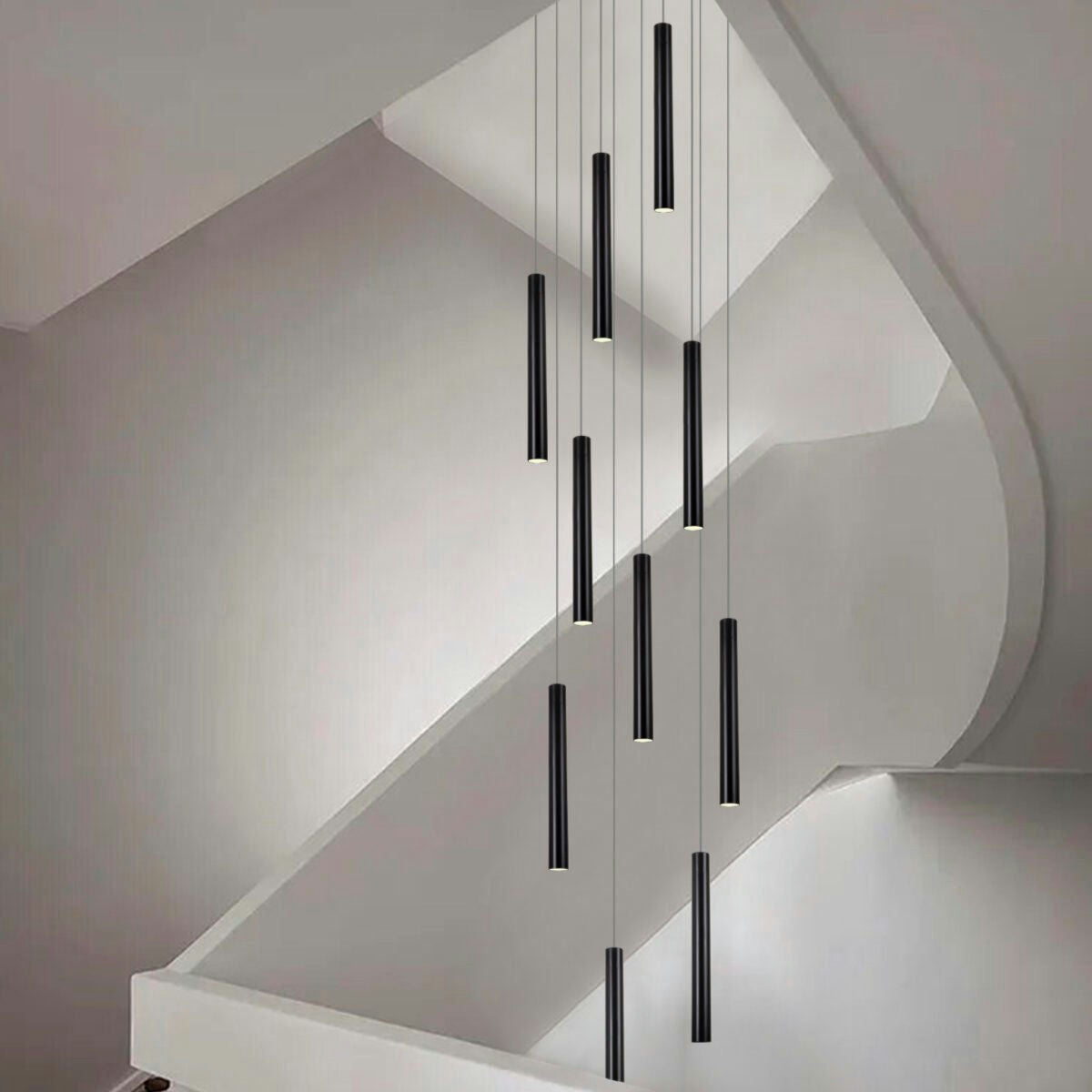 Una escalera moderna exhibe un estilo industrial y contemporáneo con varias Lámparas de Techo Colgante Moderna de Metal Negro 3048-10C-32-1 cilíndricas largas, que proyectan iluminación dirigida desde el techo.