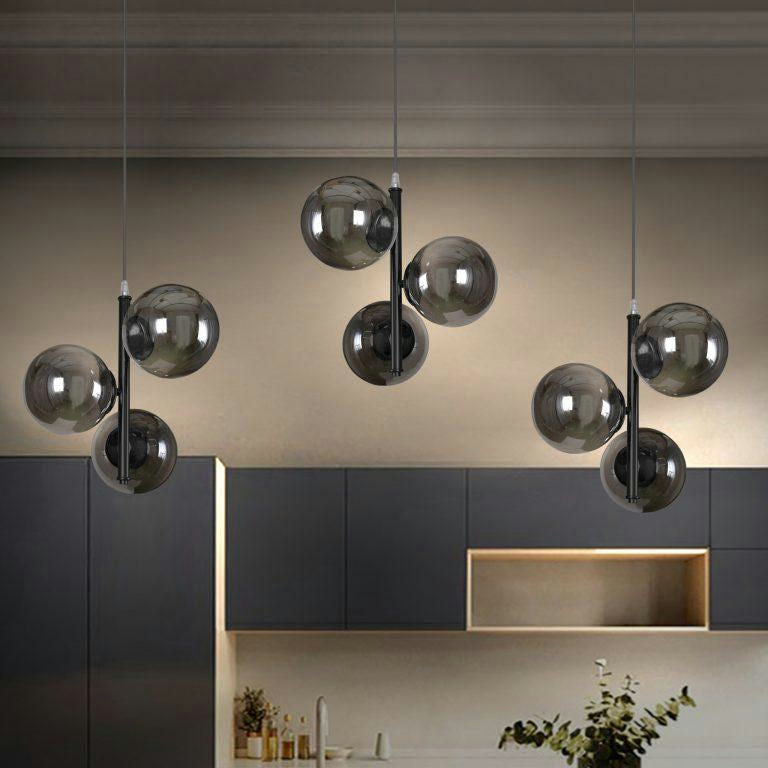 La cocina, con gabinetes oscuros y decoración minimalista, cuenta con tres lámparas de Lámpara de Techo Colgante Moderna con Cristal Ahumado 6115-3. Estos cuelgan del techo con bombillas esféricas, proporcionando una iluminación suave que realza el ambiente acogedor.