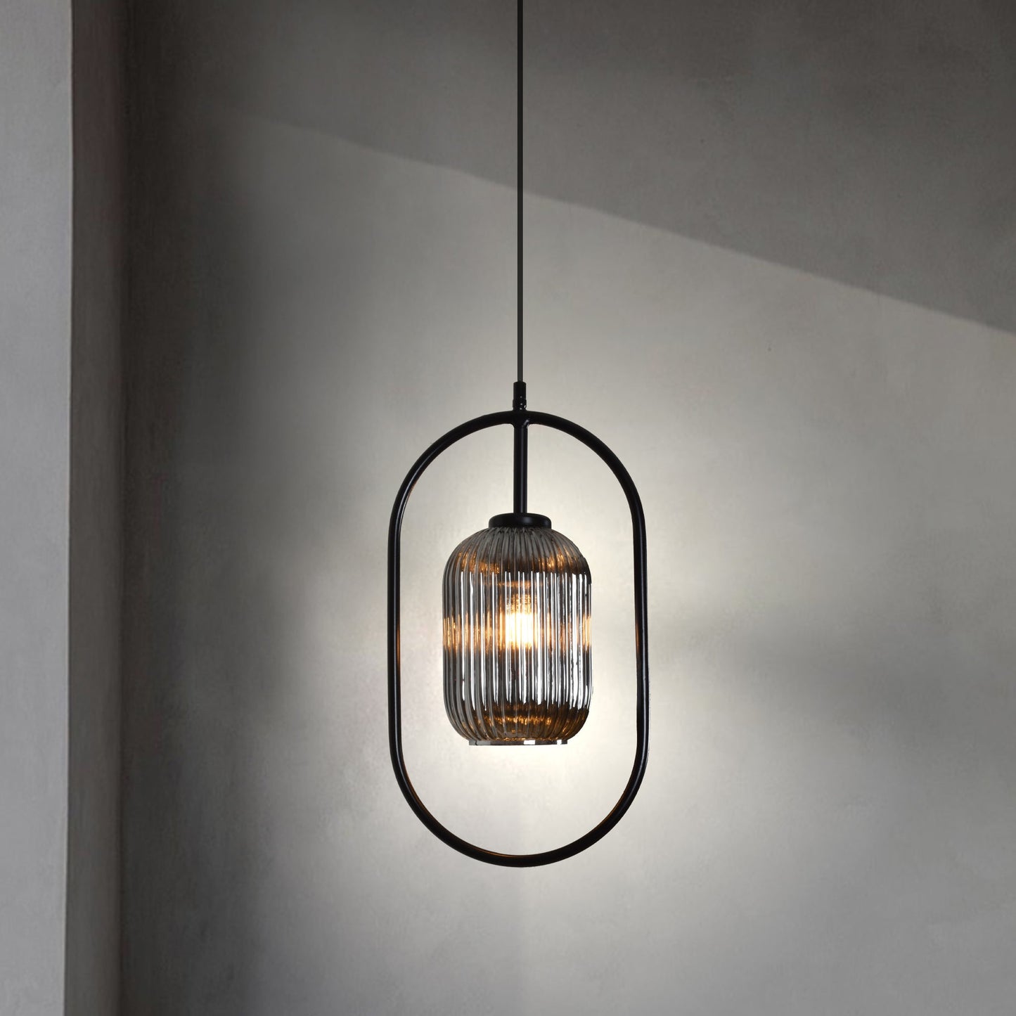La Lámpara colgante Candil Industrial (1 Luminaria) cuelga elegantemente, mostrando una carcasa de bombilla de vidrio acanalado con un elegante marco de acero y portalámparas E27, proyectando un brillo cálido en la pared minimalista.