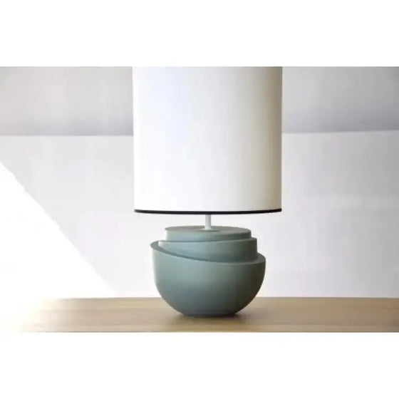 Una lámpara de mesa cerámica - Julieta con una sombra de color blanco en una mesa de madera.
