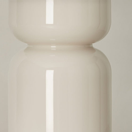 Dos jarrones apilados de vidrio esmerilado con costura visible sobre un suave fondo beige, que ofrecen una Lámpara de Mesa Got minimalista.