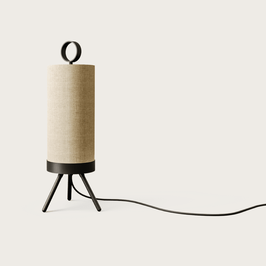 La Lámpara de Mesa Nooi, un altavoz cilíndrico de tela beige con tres patas y base y aro negros, encarna el diseño escandinavo. Un cable de alimentación se extiende desde la base.