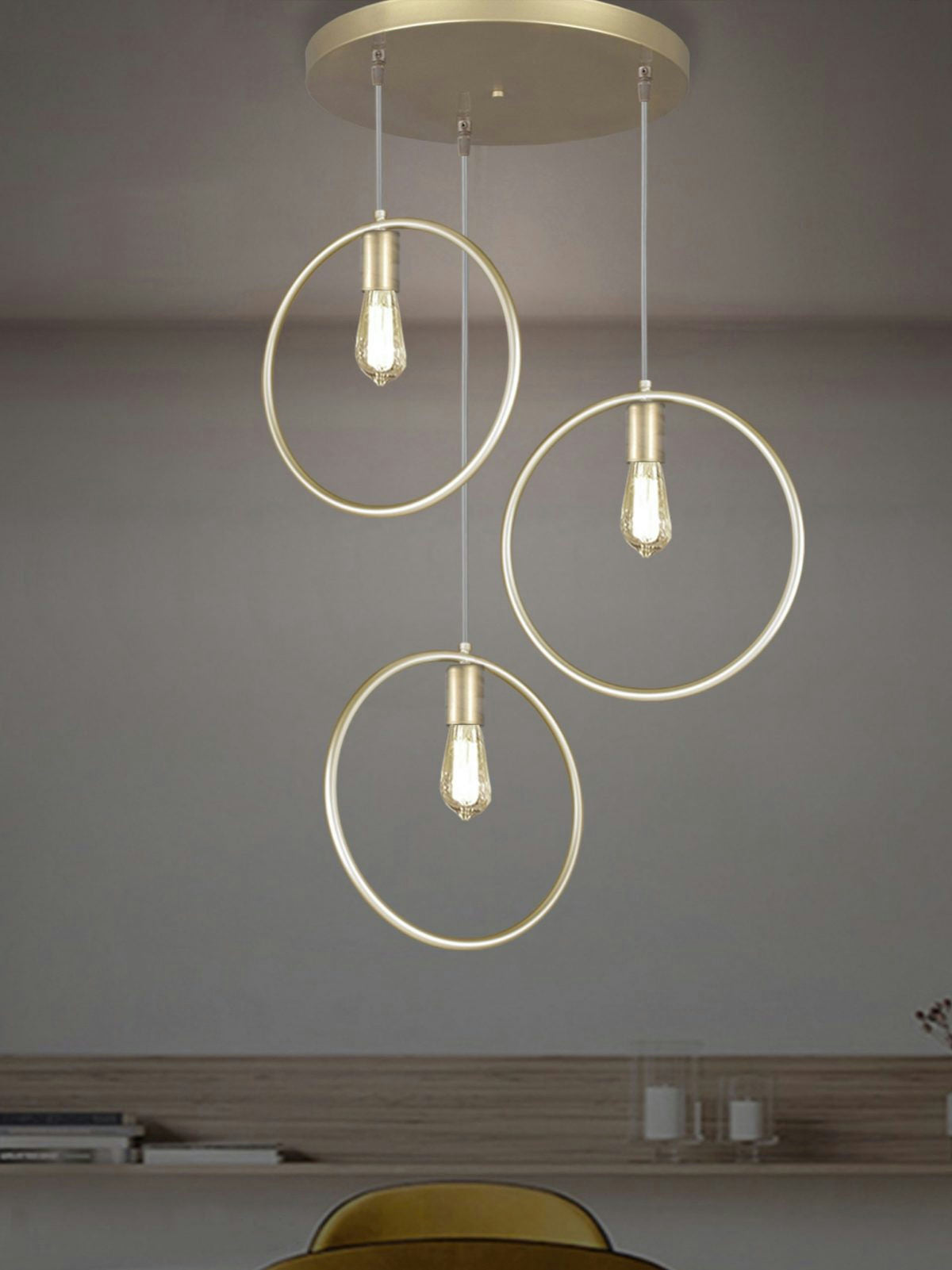 La Lámpara de Techo Colgante Moderna Oro 3134-3C presenta un diseño contemporáneo con tres bombillas expuestas en marcos circulares y un elegante acabado dorado sobre un fondo neutro.