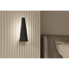 Lámpara de pared Led Bion 5W moderna montada contra una pared texturizada encima de un sofá con un cojín, presentando un diseño cómodo.