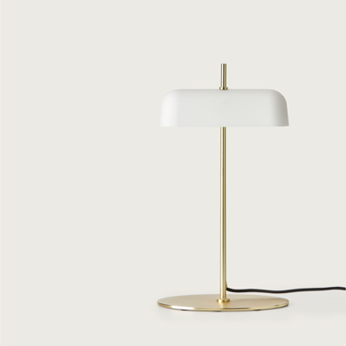 La Lámpara de mesa Atil presenta una base dorada y una pantalla blanca en forma de cúpula, que personifica el diseño minimalista moderno y captura la esencia de la iluminación escandinava.