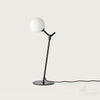 Lámpara de mesa Atom con pantalla redonda blanca, sobre fondo blanco liso, diseñada para la eficiencia energética.