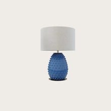  Lámpara de mesa de cerámica azul con base texturizada y pantalla E27 blanca, aislada sobre fondo blanco.