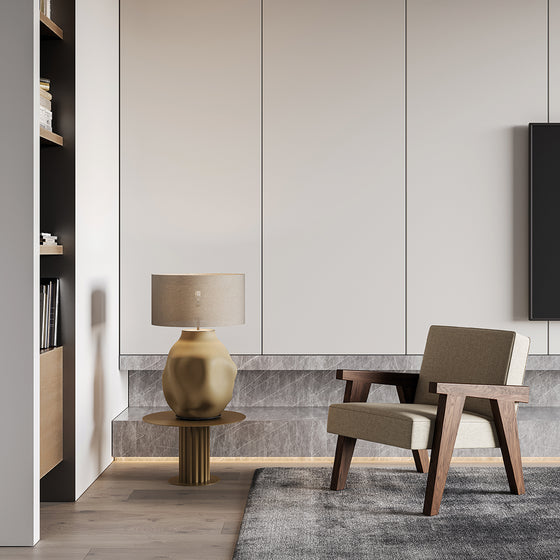 Salón moderno de diseño minimalista con sillón beige, elegante lámpara de mesa Etho dorada sobre pedestal, suelo de madera y televisor de pared.
