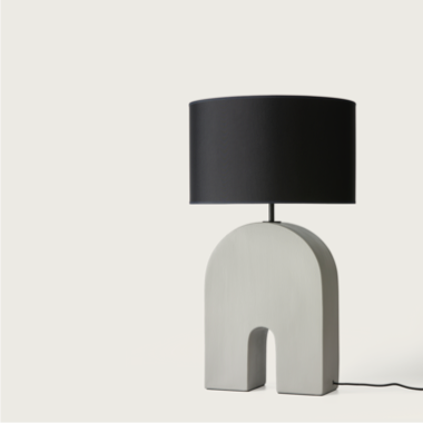 La Lámpara de mesa Home presenta una pantalla cilíndrica negra y una base única en forma de arco en un color neutro, ideal para una decoración minimalista. Esta pieza encarna la iluminación moderna, añadiendo elegancia a cualquier espacio.