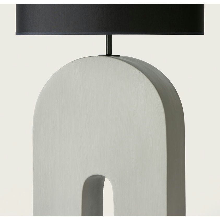 La Lámpara de mesa Home cuenta con una elegante pantalla cilíndrica negra y una sofisticada base de cerámica arqueada de color gris, que agrega elegancia a la decoración de su hogar.