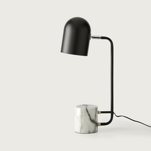  Una moderna lámpara de escritorio negra con base de mármol, sobre un fondo blanco liso, con iluminación ambiental.