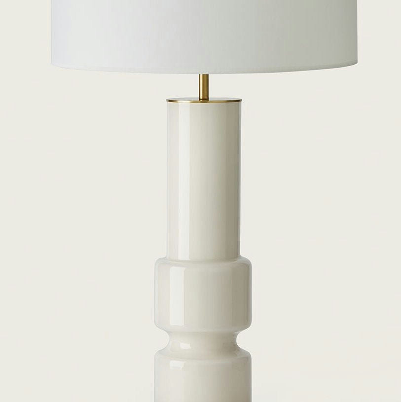 La Lámpara de mesa Lusa en color blanco, con base cilíndrica y pantalla blanca, muestra un diseño clásico sobre un fondo liso.