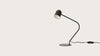 Lámpara de mesa Pipe negra moderna con cuello curvado y base circular, apagada, sobre un fondo blanco liso, con un diseño minimalista.