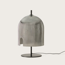  Lámpara de mesa Porta-L moderna con pantalla plateada acanalada y base negra sobre fondo blanco, perfecta para iluminación ambiental.
