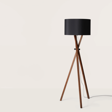 La Lámpara de pie Cot, de diseño clásico, presenta patas de madera y pantalla negra, sobre un fondo blanco liso. Un cable de alimentación visible enfatiza su iluminación efectiva.