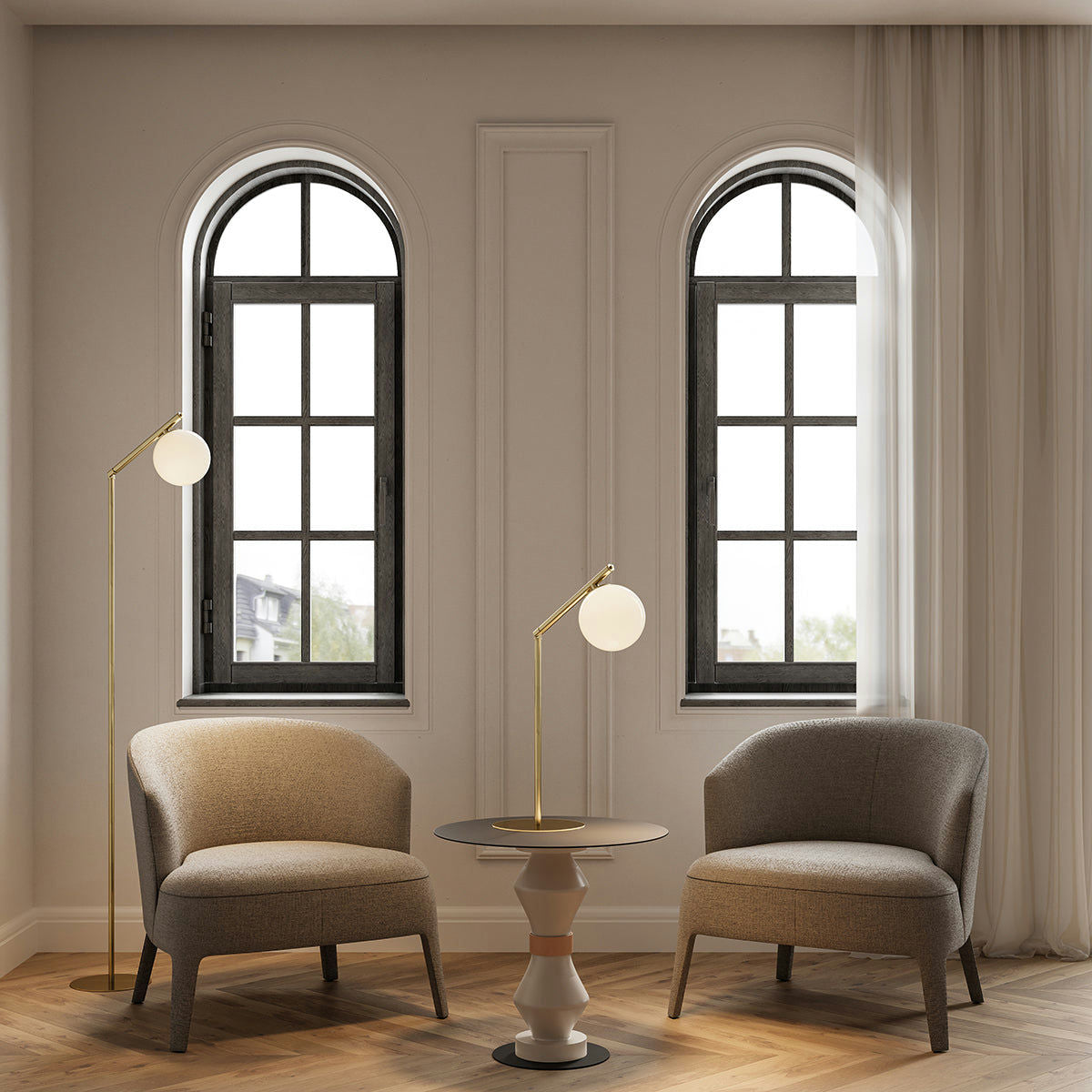 Dos sillones grises se sitúan frente a una mesa redonda con lámpara de mesa, situada frente a dos ventanas arqueadas. El suelo de madera clara y la lámpara de pie Endo alta realzan el ambiente acogedor, asegurando una iluminación adecuada en todo el espacio.