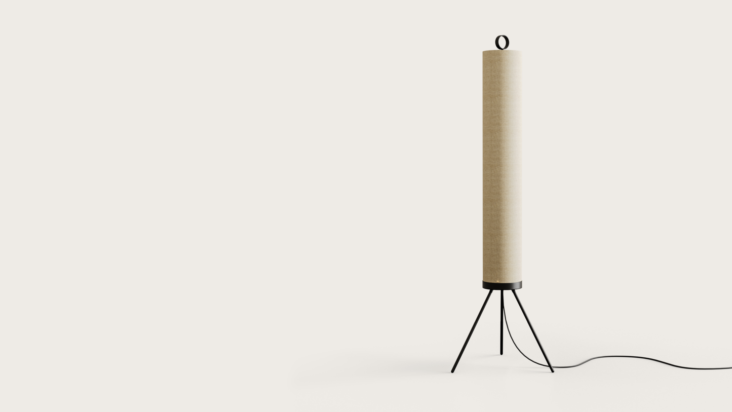 La Lámpara de pie Nooi presenta un diseño alto y cilíndrico en color beige sobre un elegante trípode negro con un lazo en la parte superior, que irradia un estilo moderno. Su cable de alimentación se extiende elegantemente desde la base, evocando el aspecto de una lámpara contemporánea.